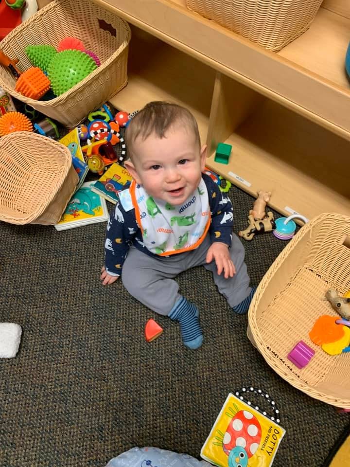 Child sitting on floor surrounded by toys and baskets