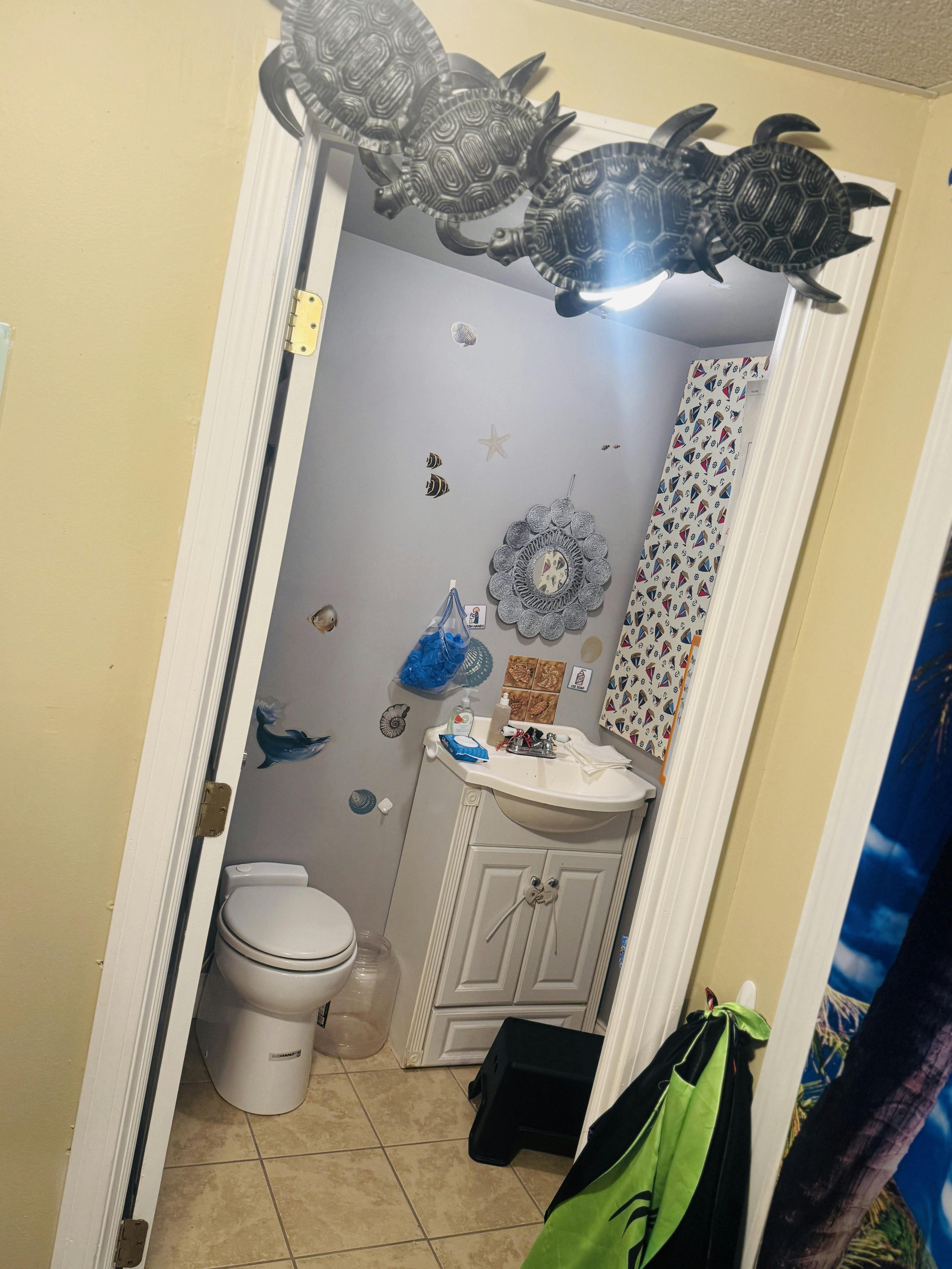Bathroom with toilet, sink, and shower curtain, decorated with sea-themed items