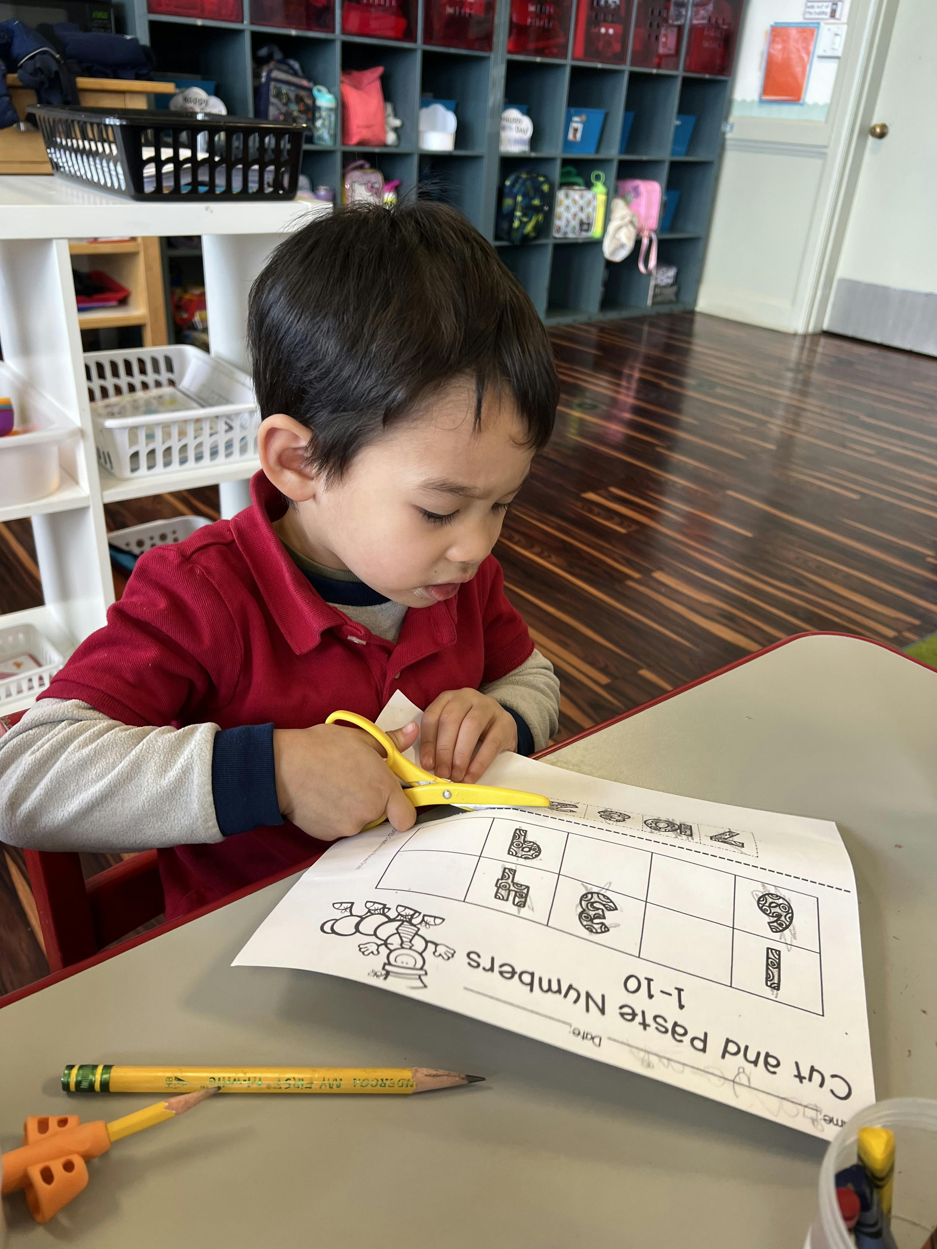 Child cutting paper with scissors in a classroom