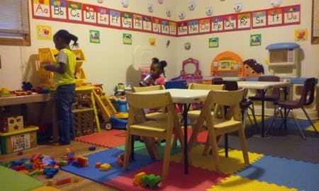 Two children playing in a classroom with toys and tables