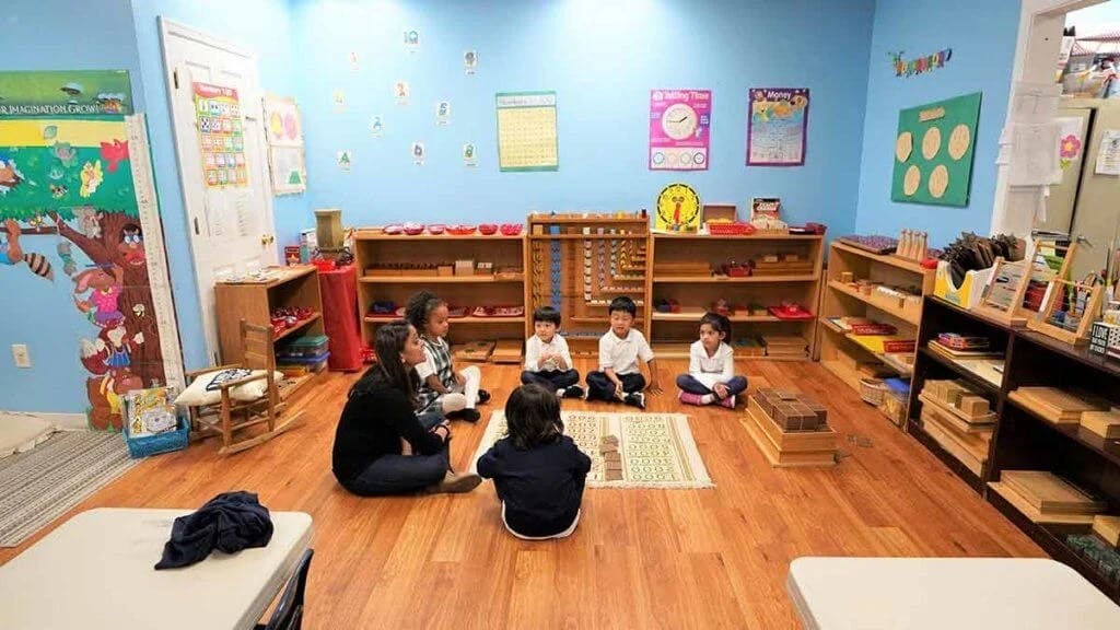 Children and a person sitting on the floor in a classroom