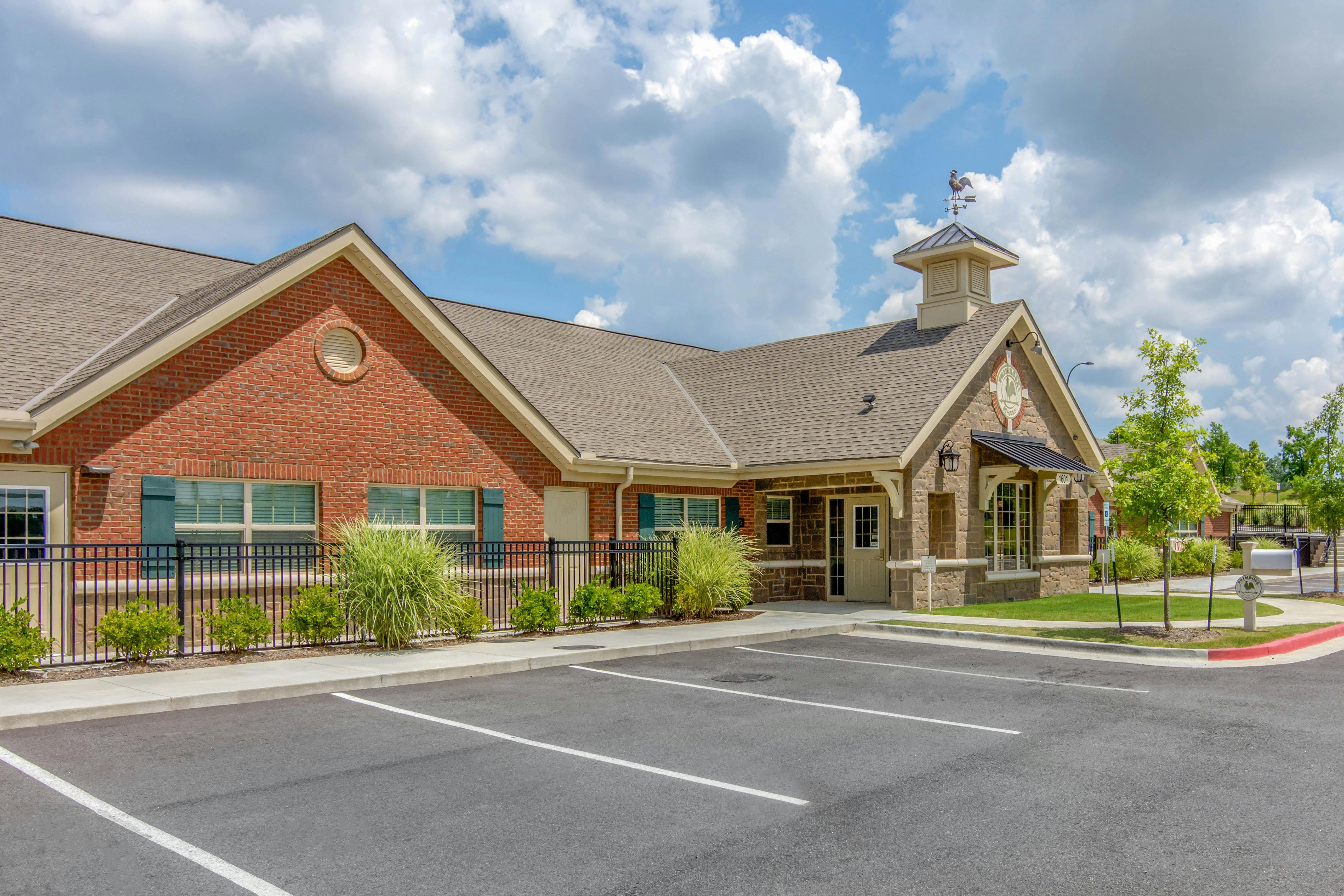 Brick building with a stone entrance, a weathervane, and an empty parking lot