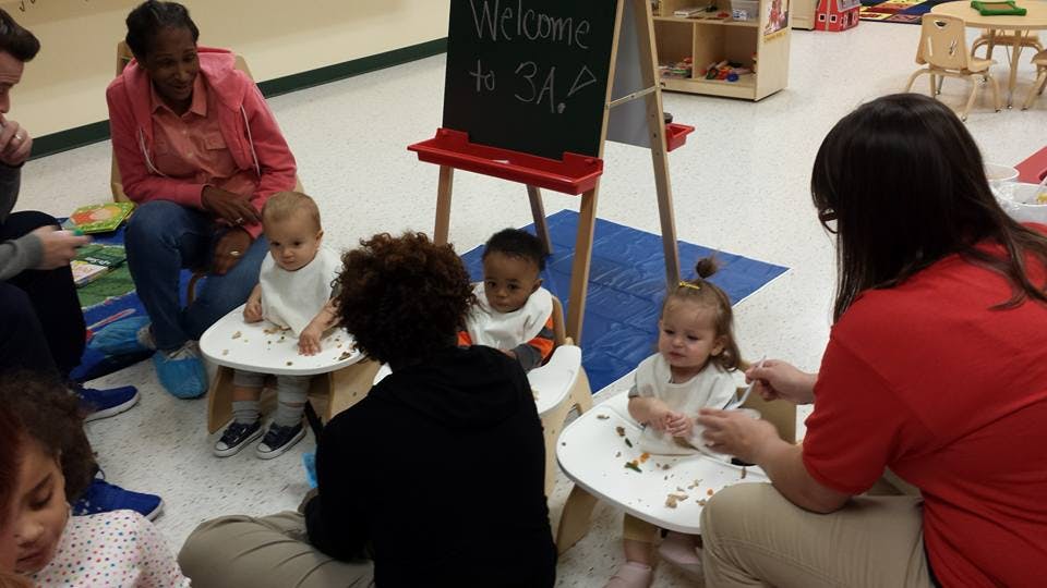 Adults with children in high chairs in a classroom