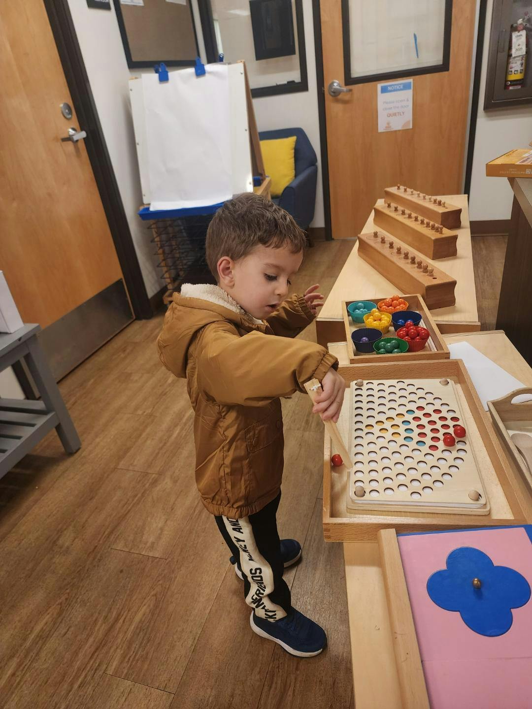 Child playing with a wooden peg board and small colored balls