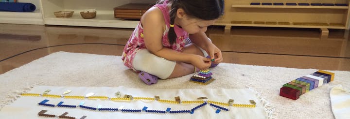 Child sitting on floor, working with small objects on a mat