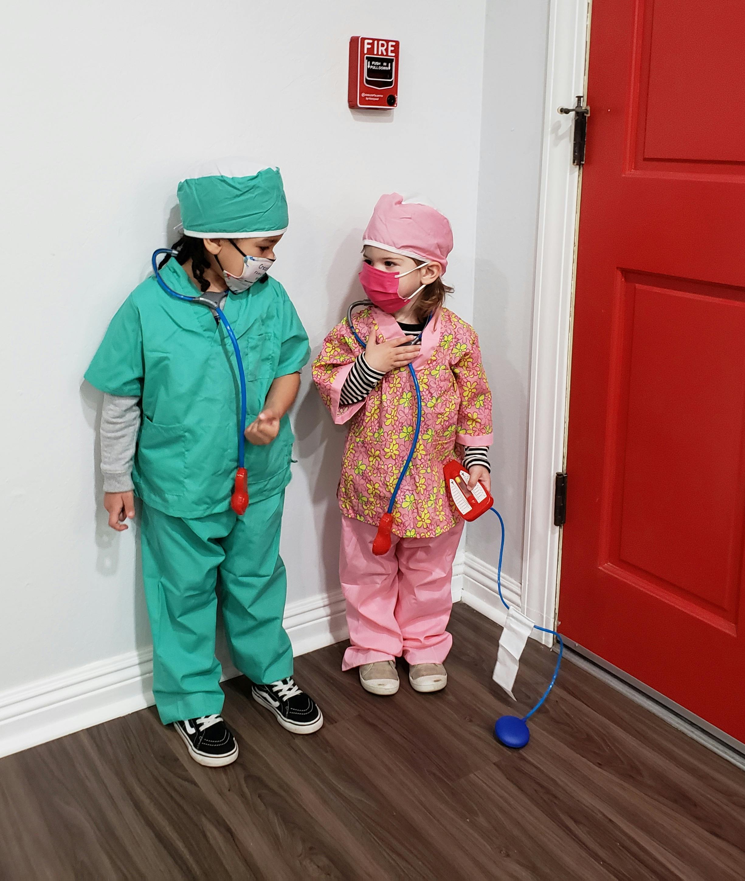 Two children in doctor costumes with stethoscopes and masks