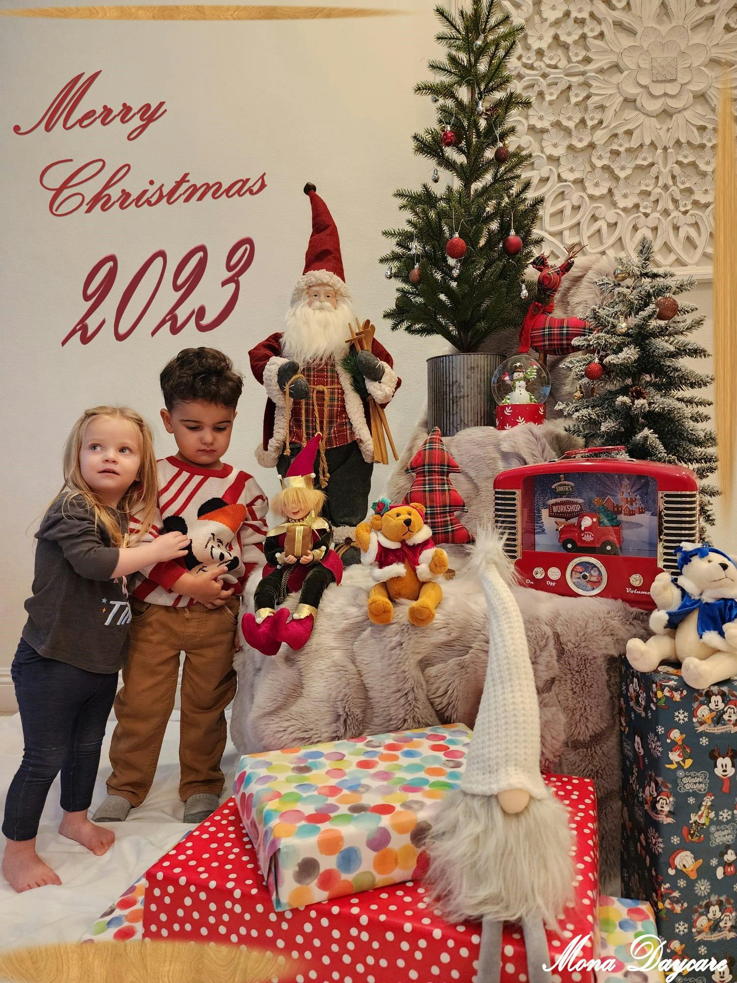 Two children with Christmas decorations and gifts, text "Merry Christmas 2023"