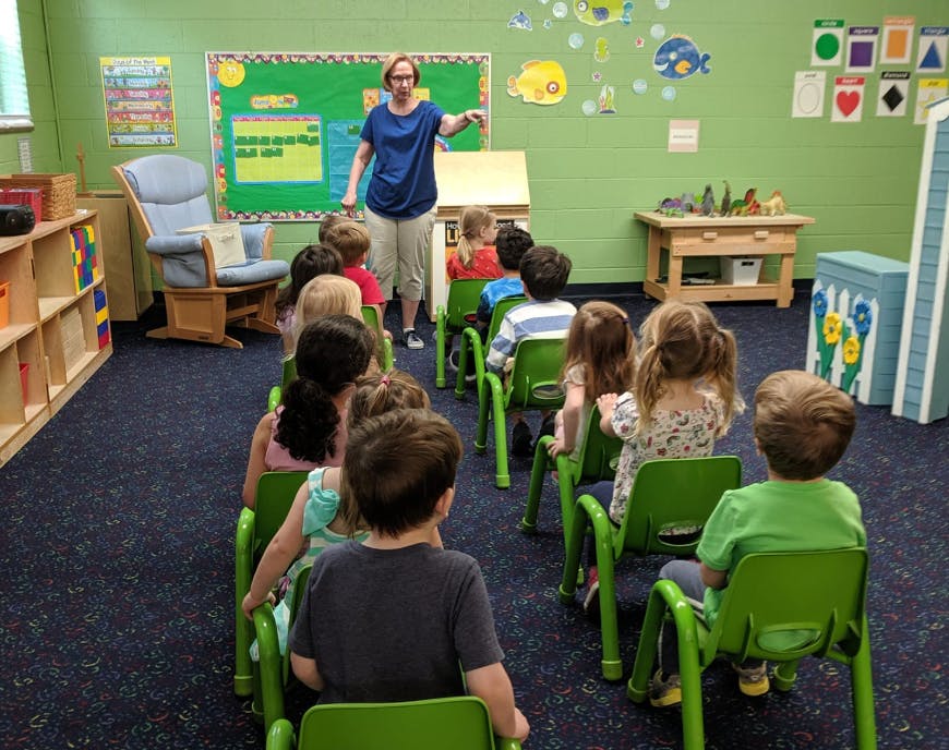 Adult teaching a group of children in a classroom