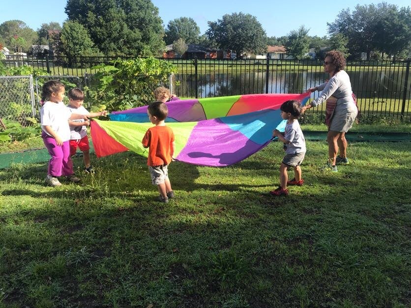 Adult and children playing with a colorful parachute outdoors
