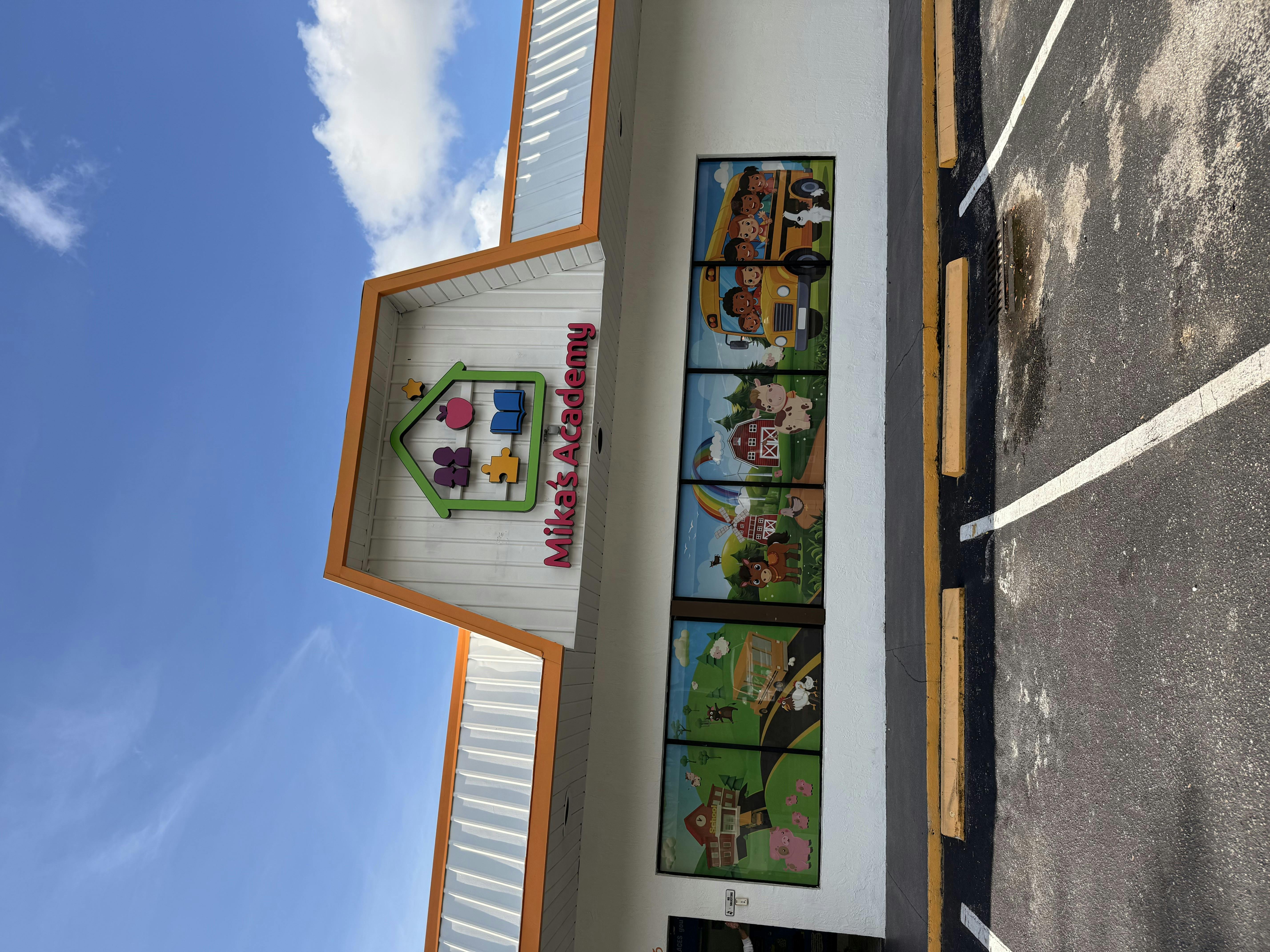 Building exterior with "Mika's Academy" sign and cartoon window decals
