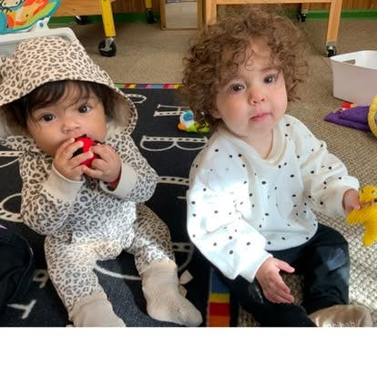 Two children sitting on an alphabet rug playing with small toys