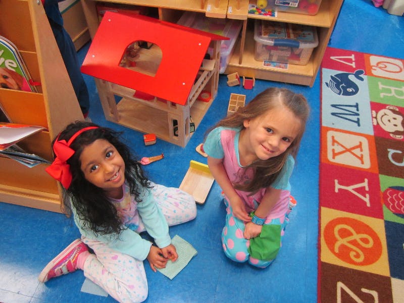 Two children kneeling on the floor in a classroom