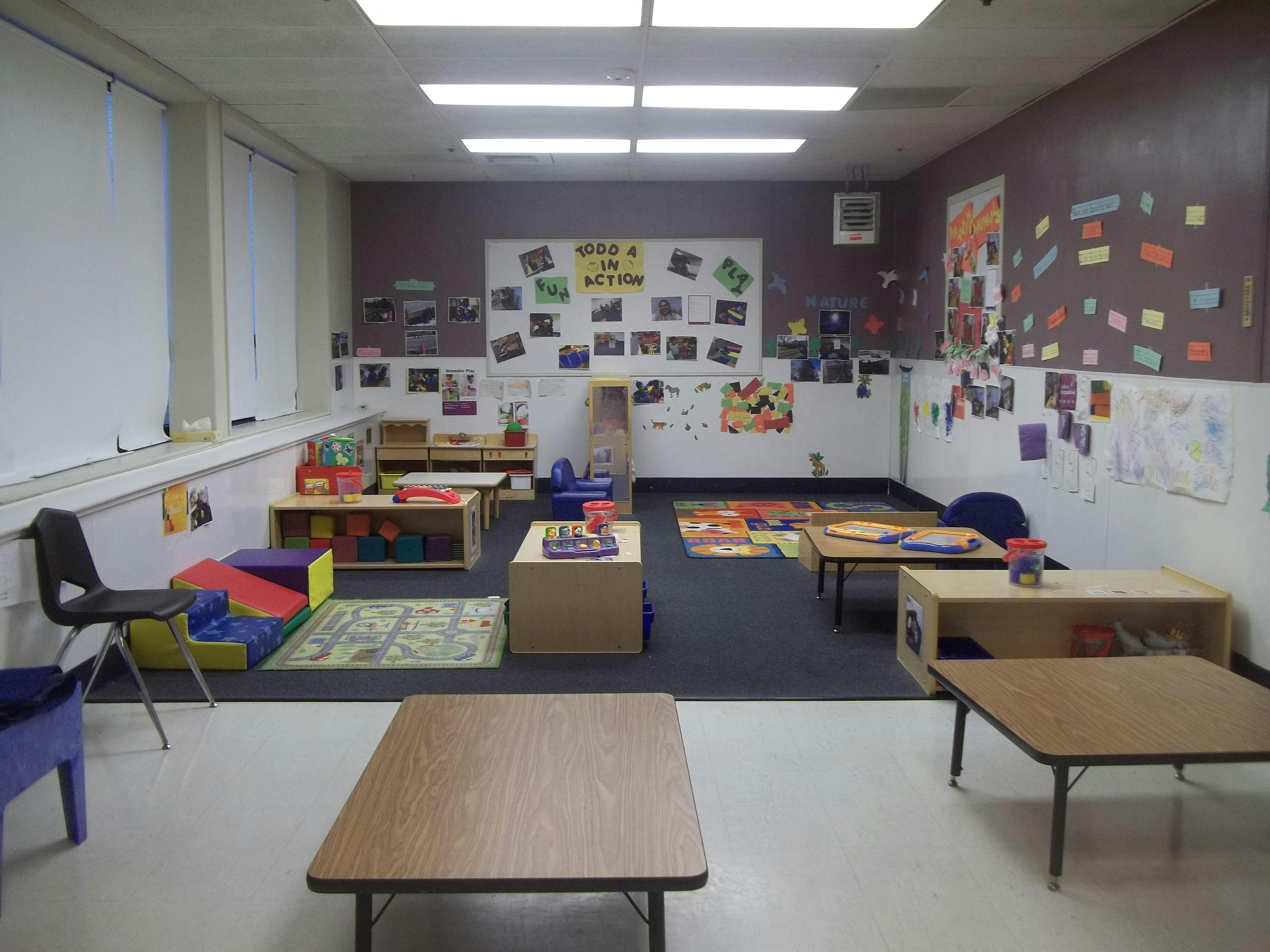 Classroom with low tables, chairs, and colorful play mats on the floor