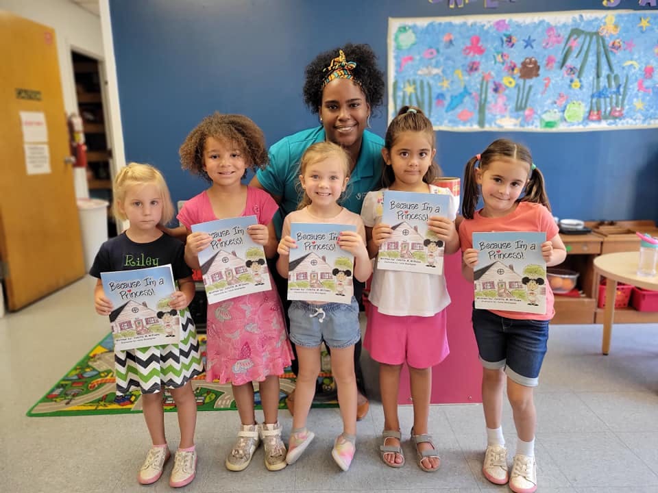 Adult and five children holding books in a classroom