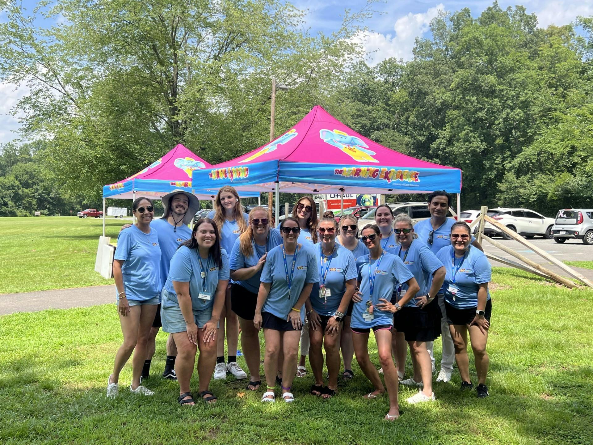 Group of people in blue shirts standing in front of pink tents