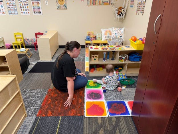 Adult and child playing with sensory floor tiles in a classroom