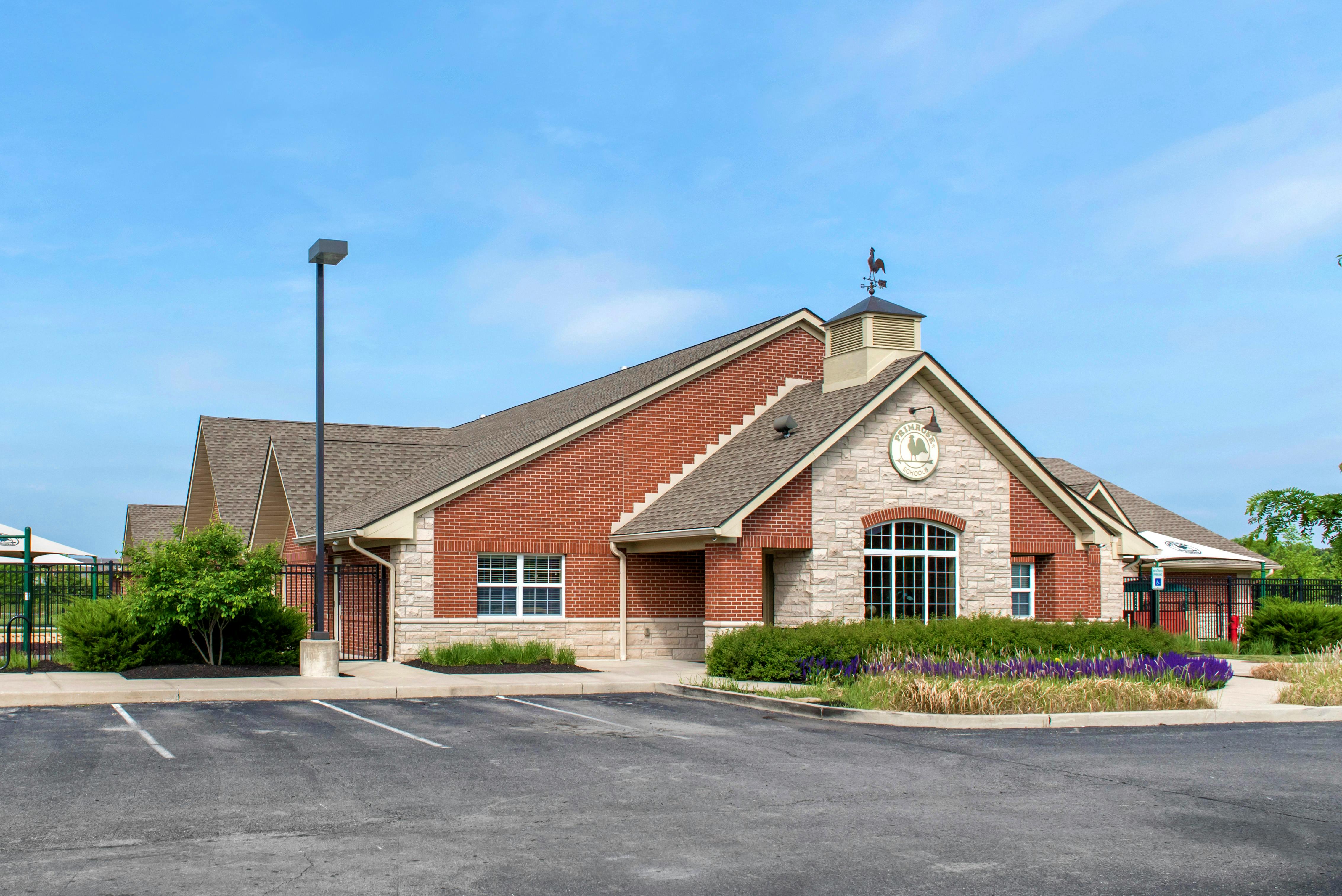 Brick and stone building with a weather vane, and a sign that says "Primrose Schools"
