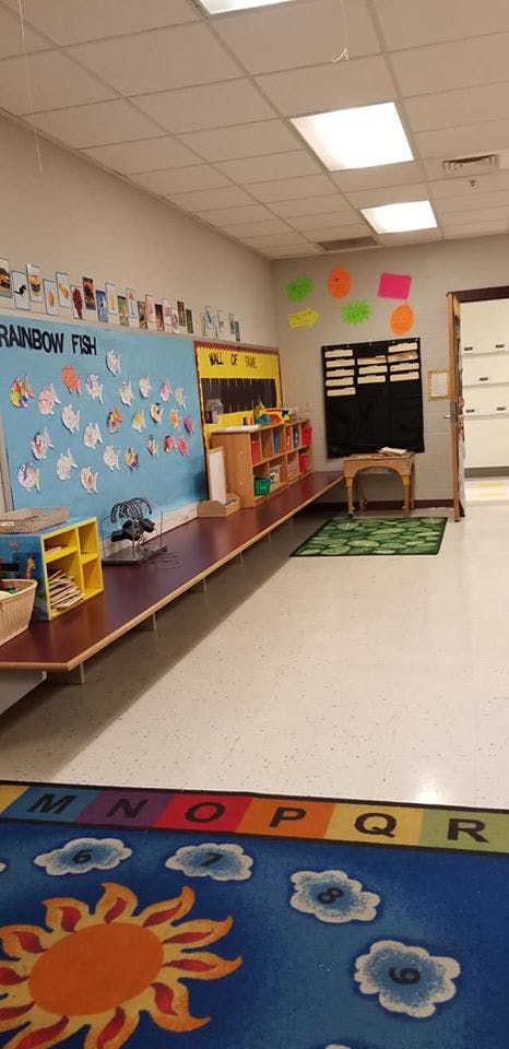 Classroom with a bulletin board, shelves, and an alphabet rug