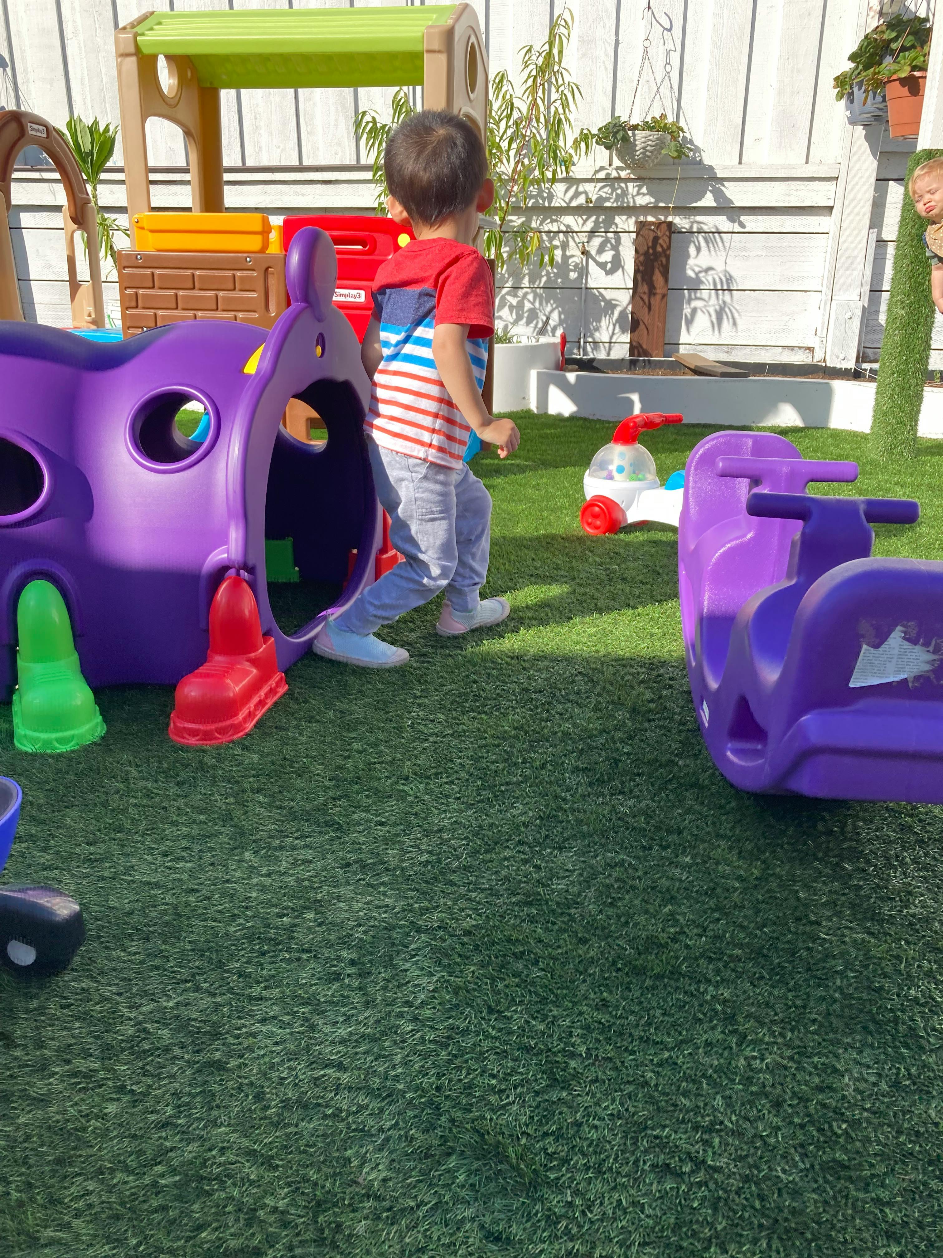 Child walking on artificial grass near purple play equipment