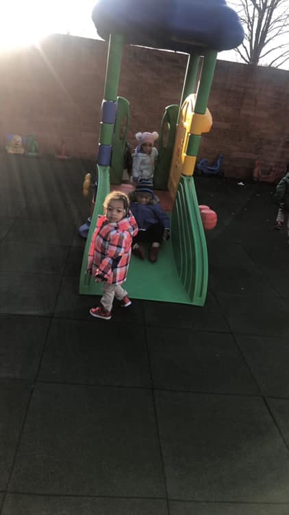 Child walking away from a playground slide with other children in the background