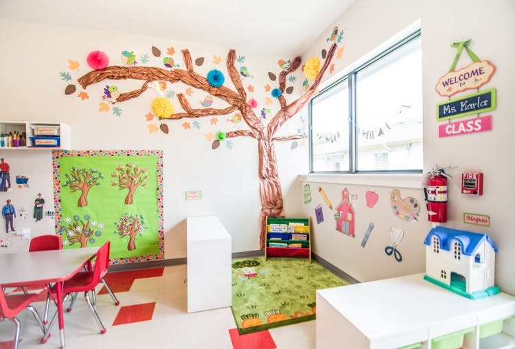 Classroom with a tree mural on the wall and small tables and chairs