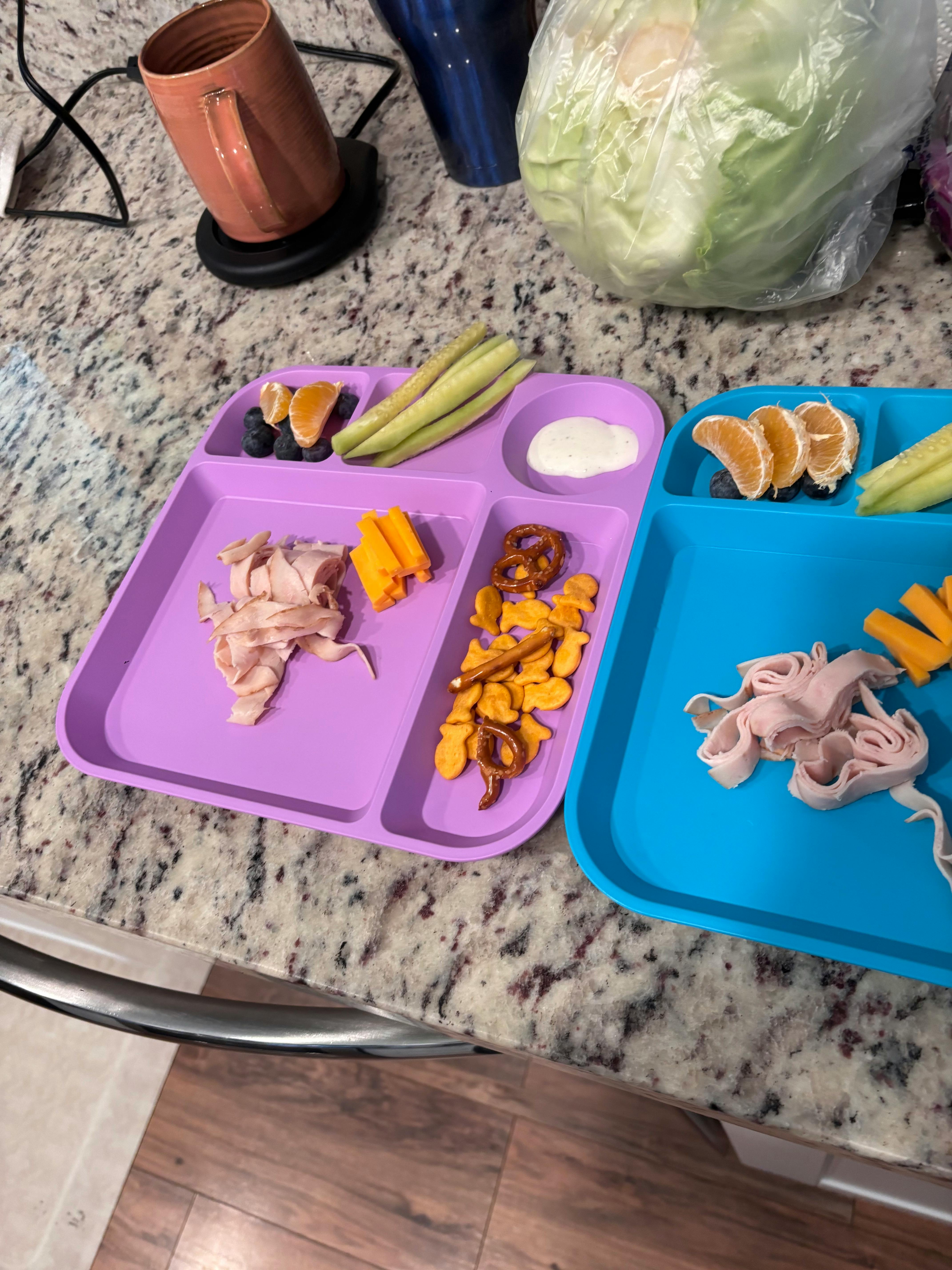 Two divided plates with snacks on a counter