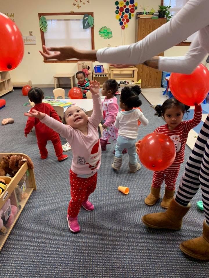 Children playing with red balloons in a classroom