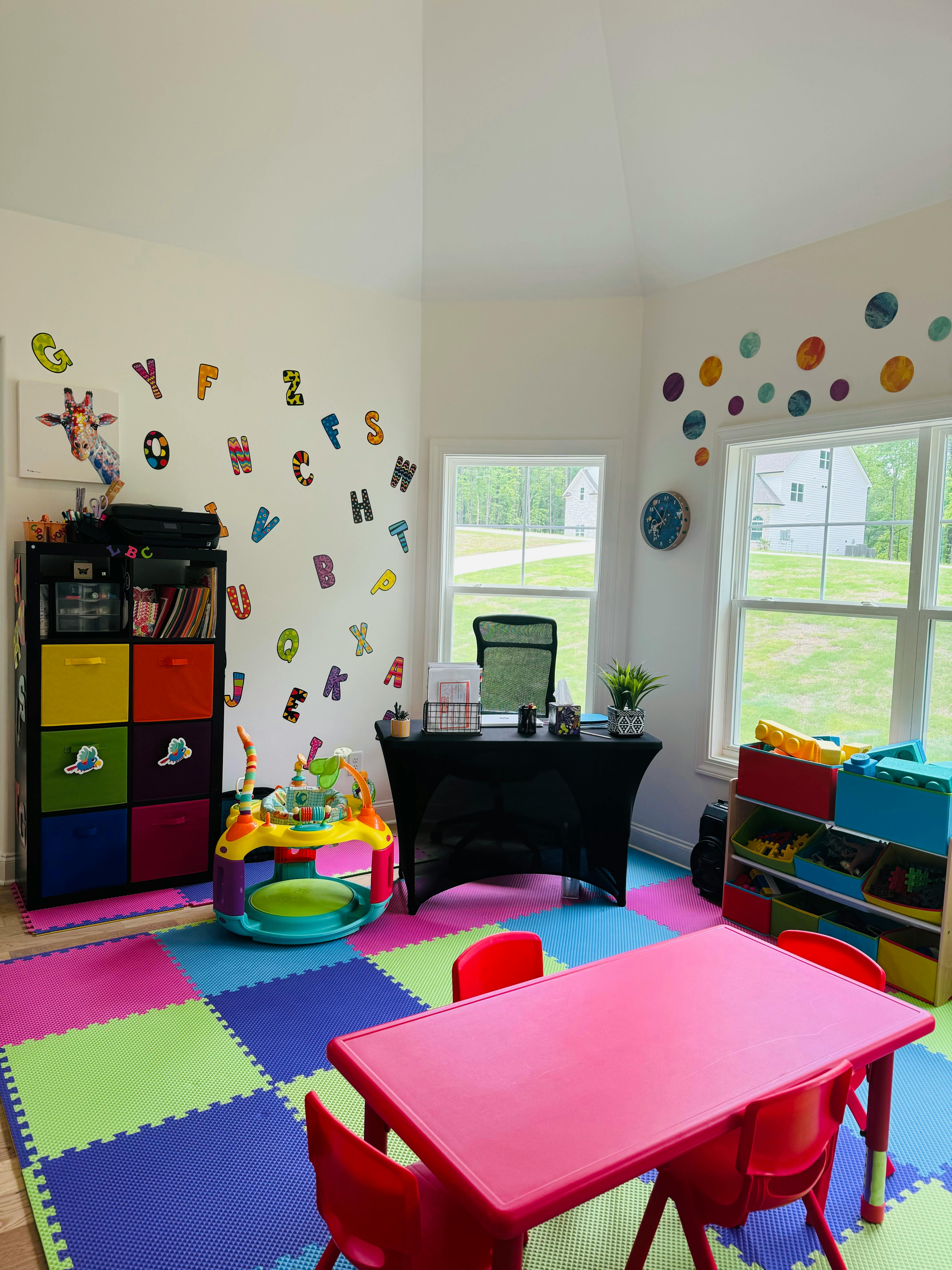 Playroom with colorful floor mats, a small red table and chairs, and alphabet wall decals