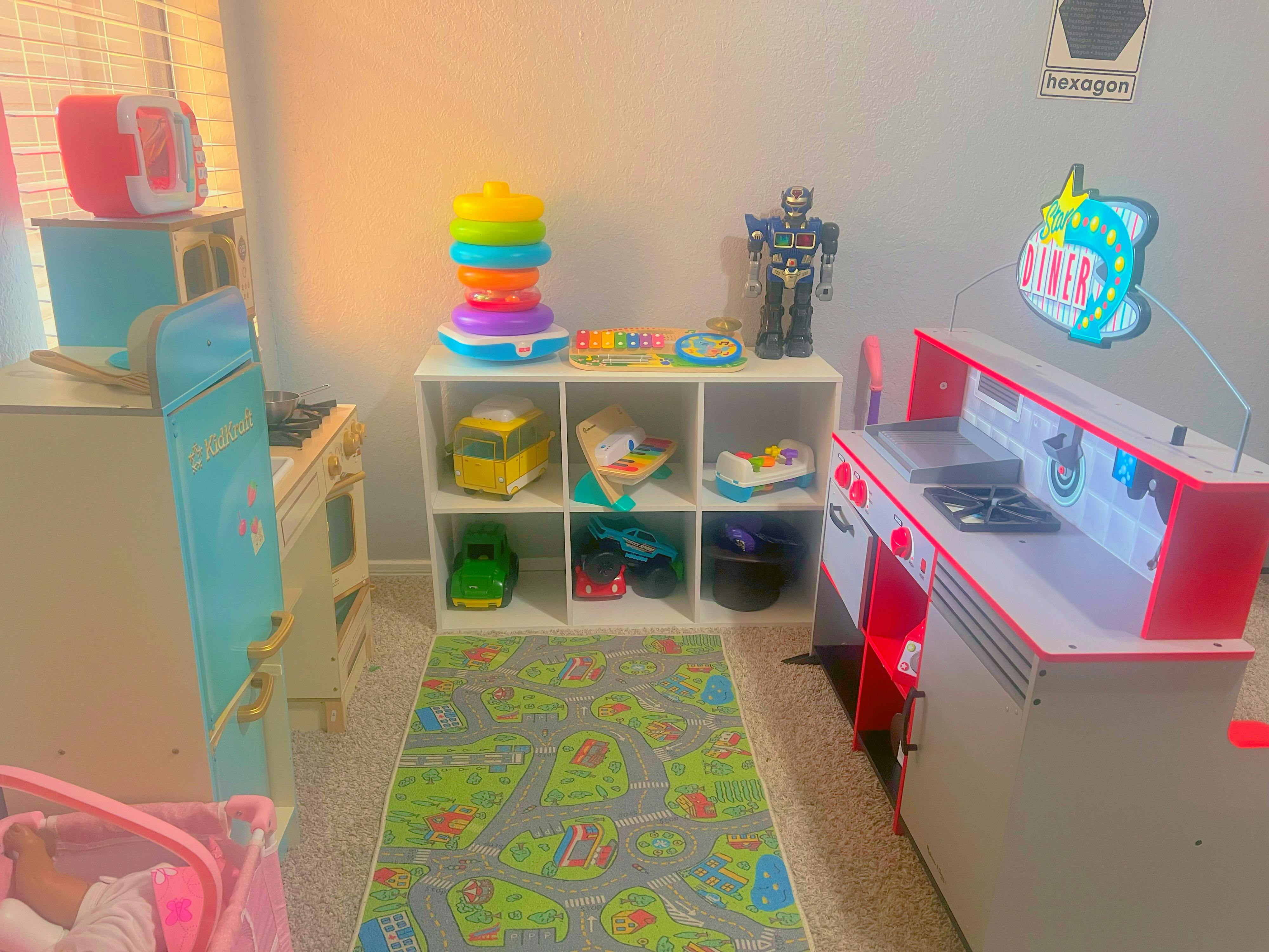 Playroom with toy kitchen, shelves of toys, and a colorful rug