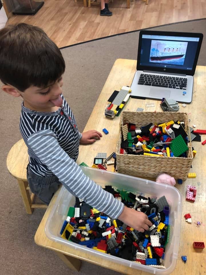 Child playing with building blocks at a table with a laptop