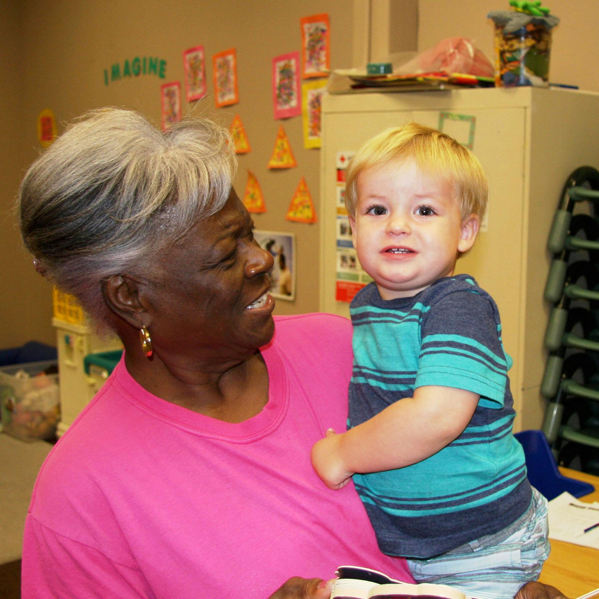 Adult holding a child in a classroom