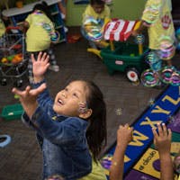 Child reaching up with hands, looking at bubbles