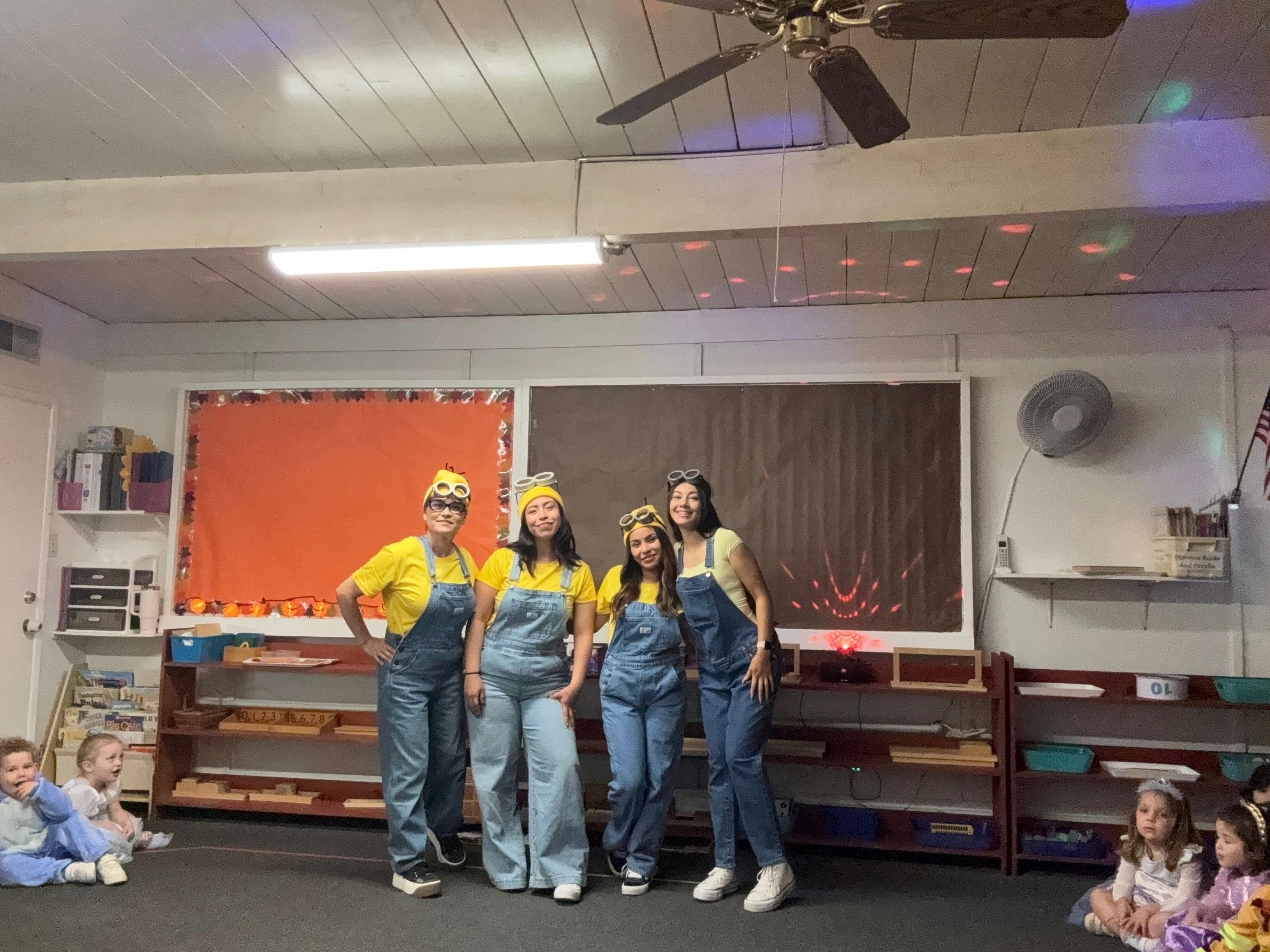 Four people dressed as minions in a classroom