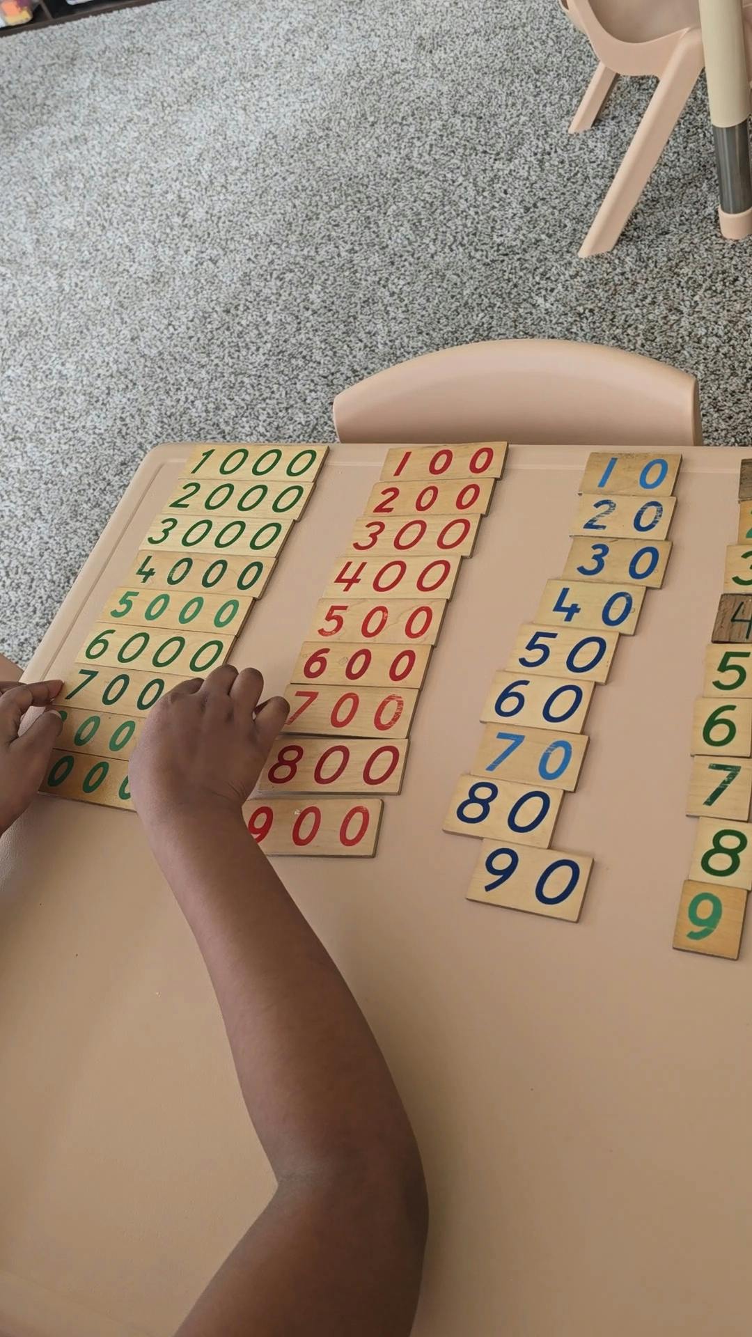 Child placing numbered tiles on a table