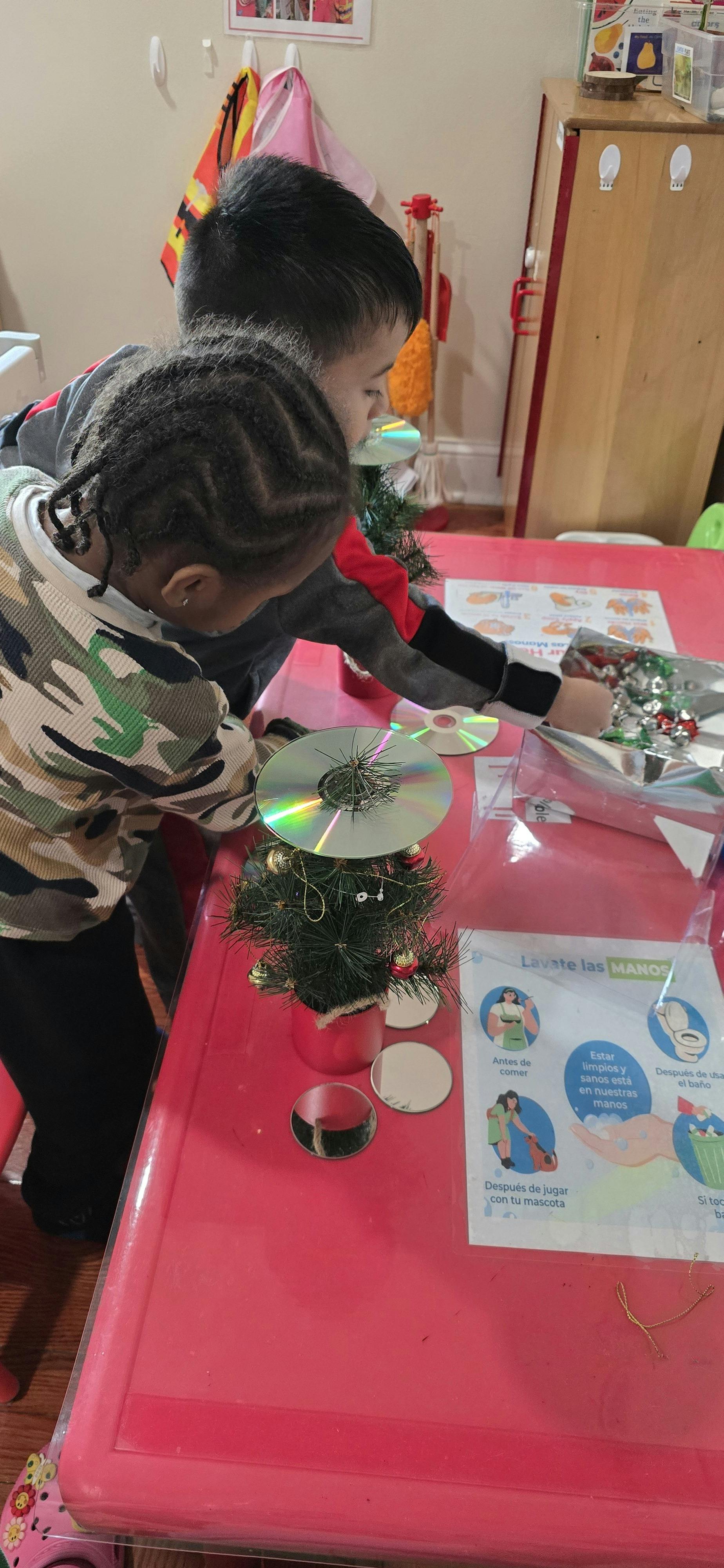Two children making crafts on a red table