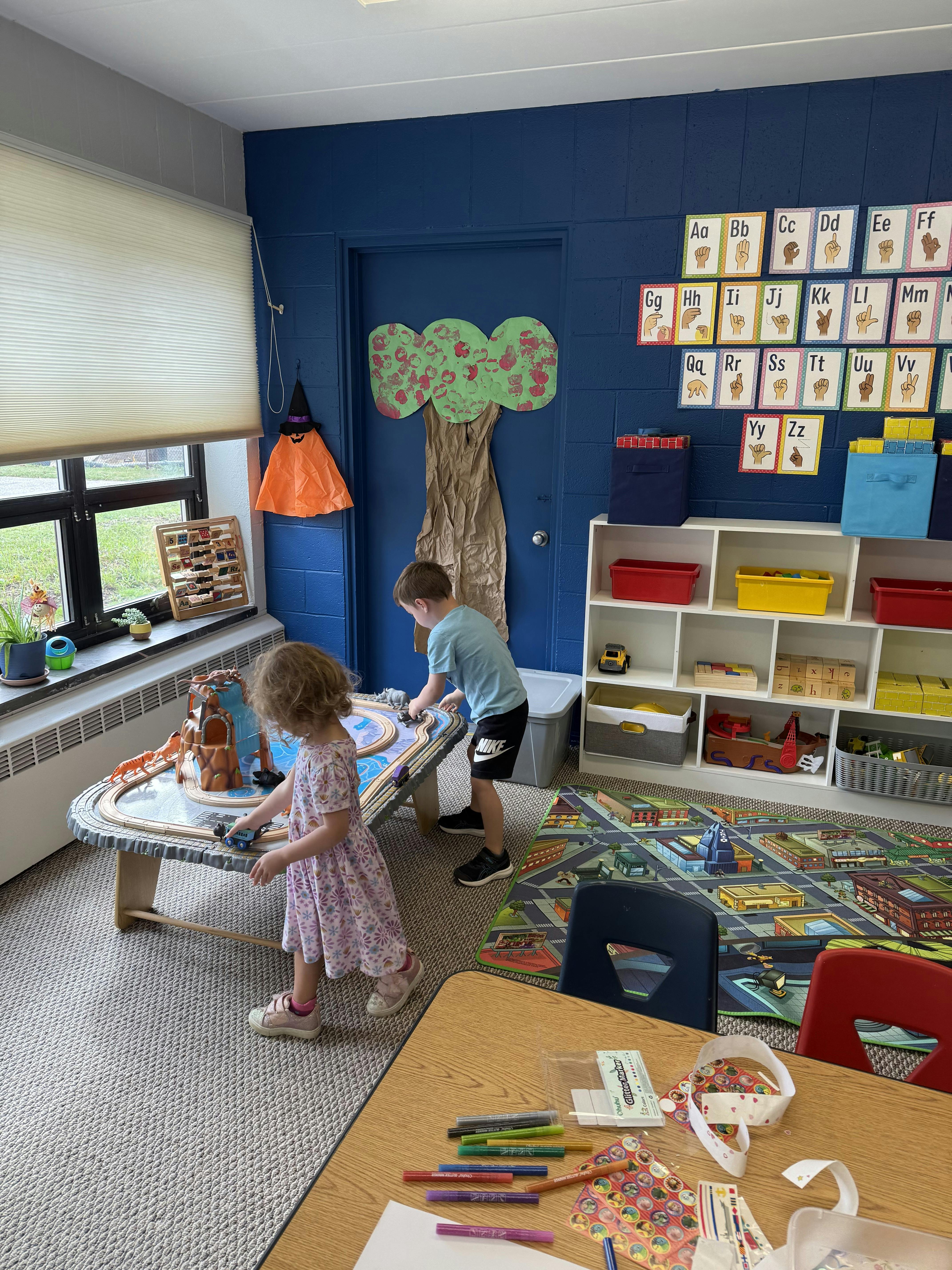 Two children playing with a train set in a classroom