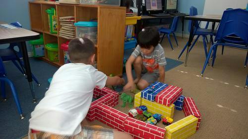 Two children playing with toy blocks in a classroom