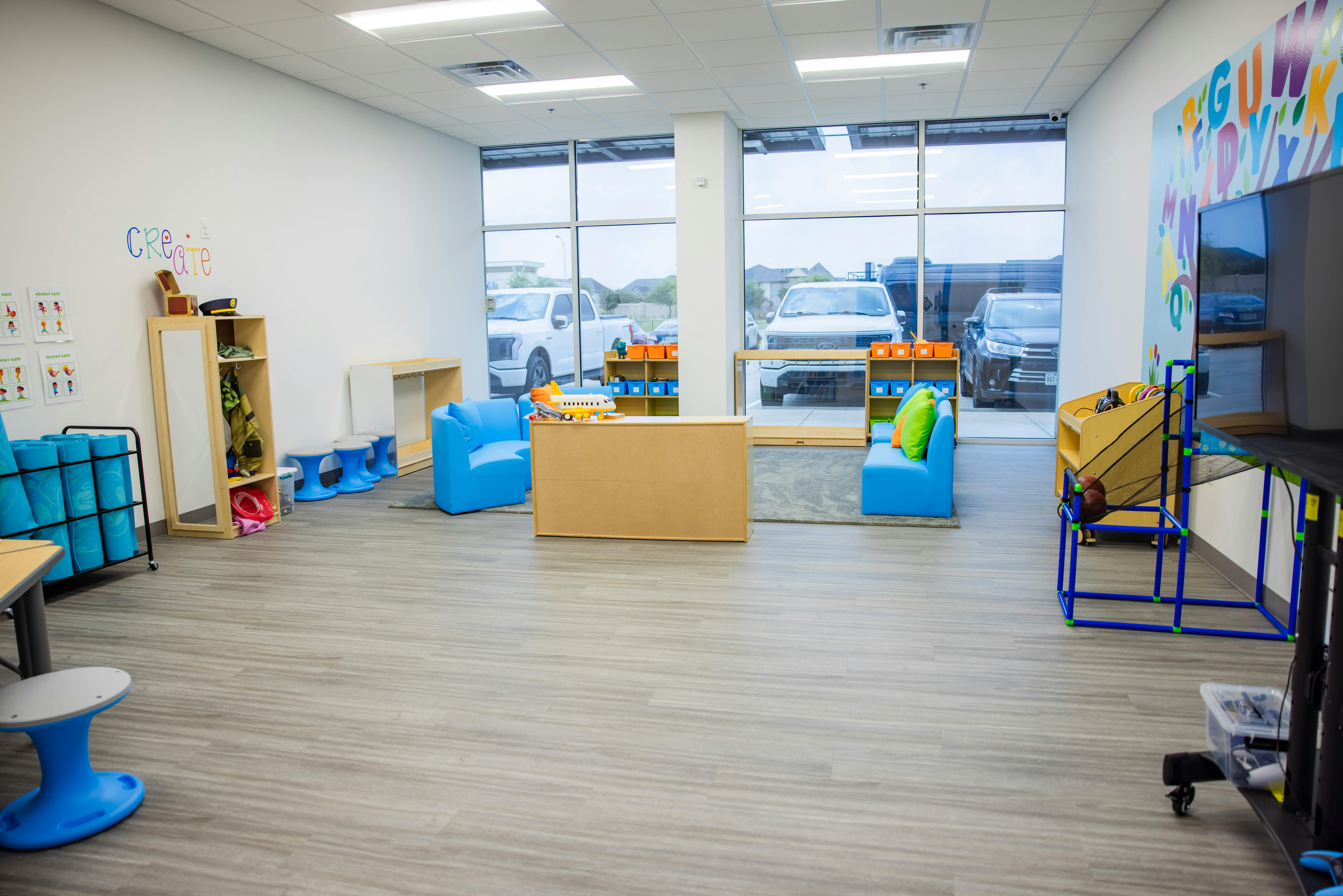 Empty classroom with large windows, blue chairs, and shelves