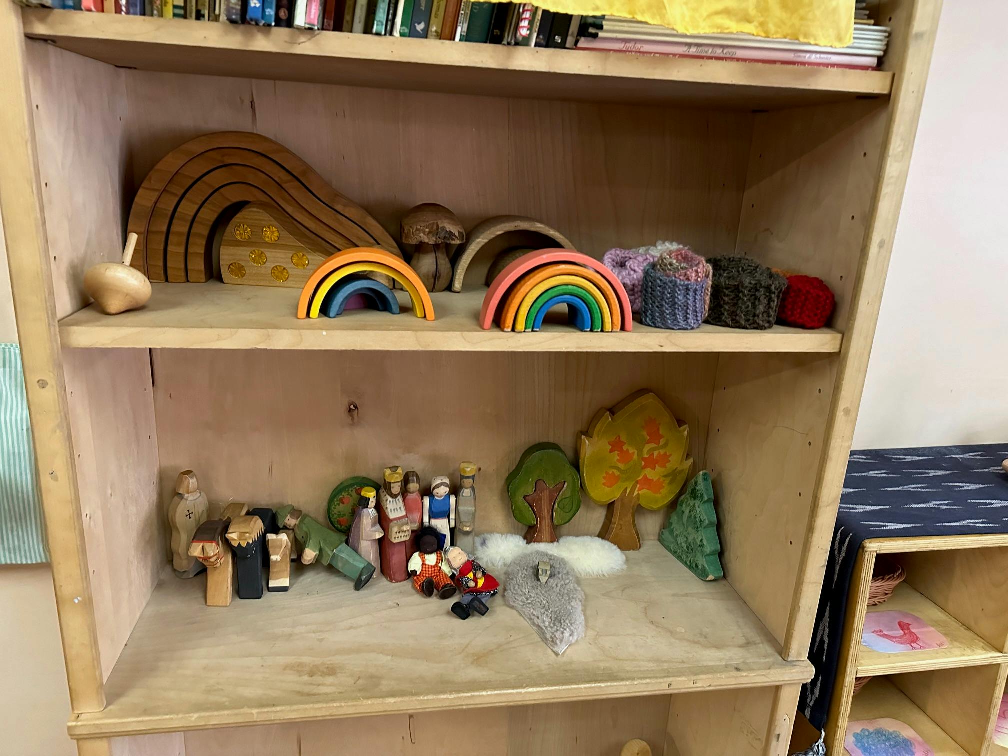 Wooden shelf with various toys including rainbows, trees, and figures