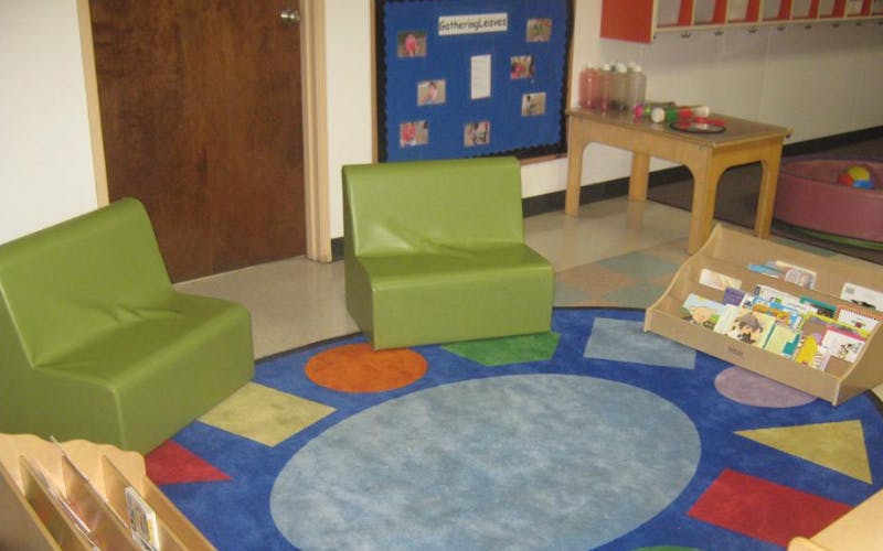 Classroom corner with green chairs and a colorful rug
