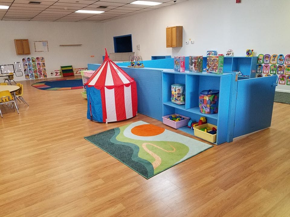 Playroom with a red and white striped tent and blue shelving units with shelves