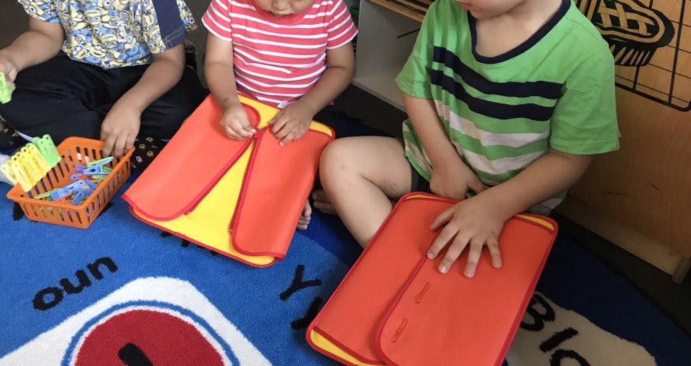 Children playing with red and yellow mats on a blue rug