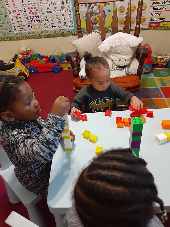 Three children playing with colorful building blocks at a table