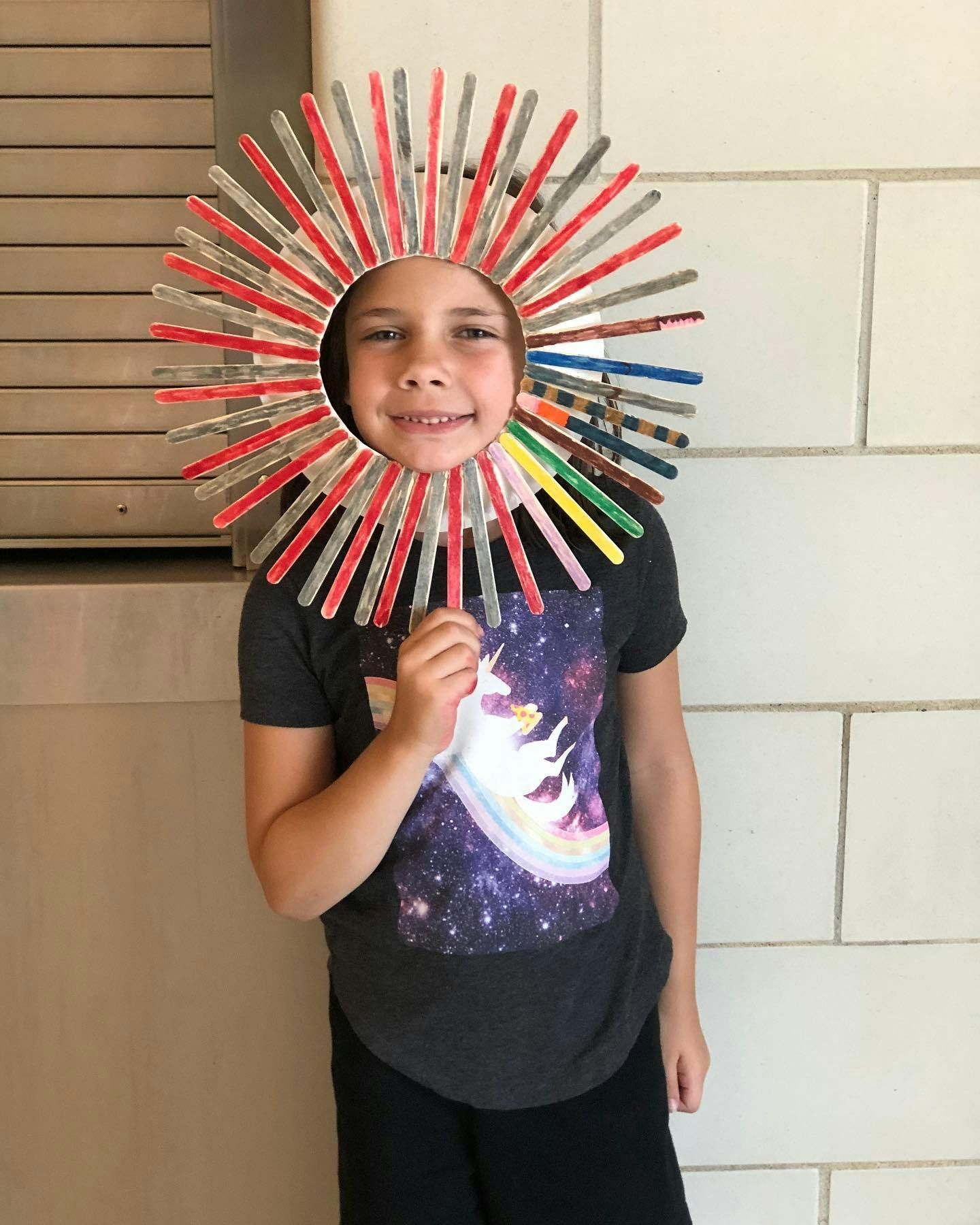 Child wearing a sun-like costume made of clothespins
