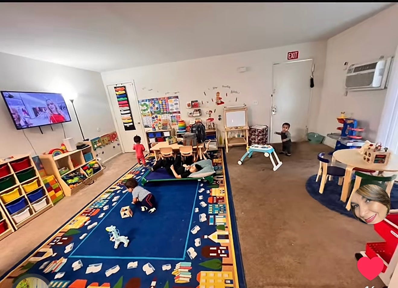 Children in a classroom, one child on a play mat, another playing with blocks