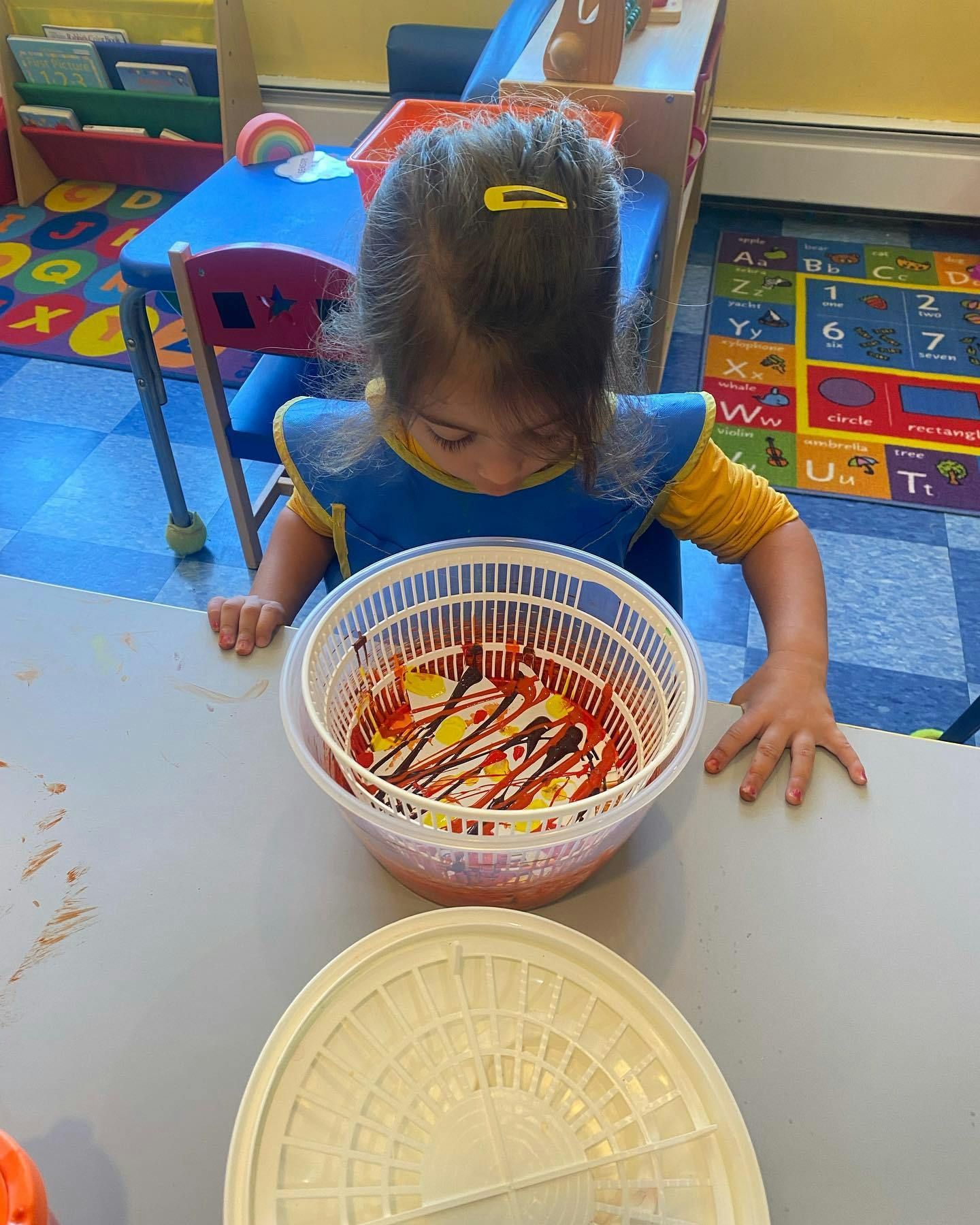 Child looking at a salad spinner with paint inside
