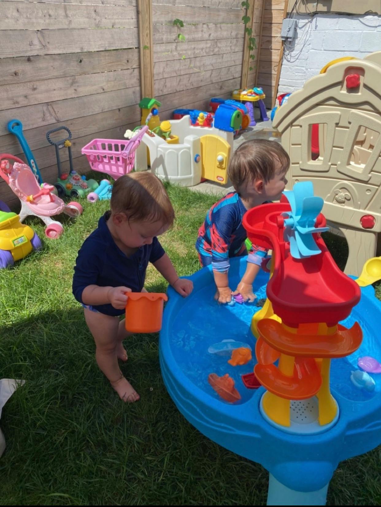 Two children playing with a water table outdoors