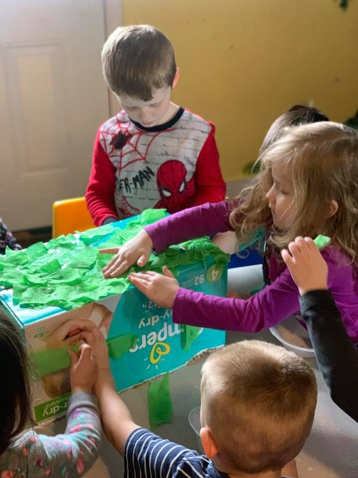 Children working on a craft project with green paper
