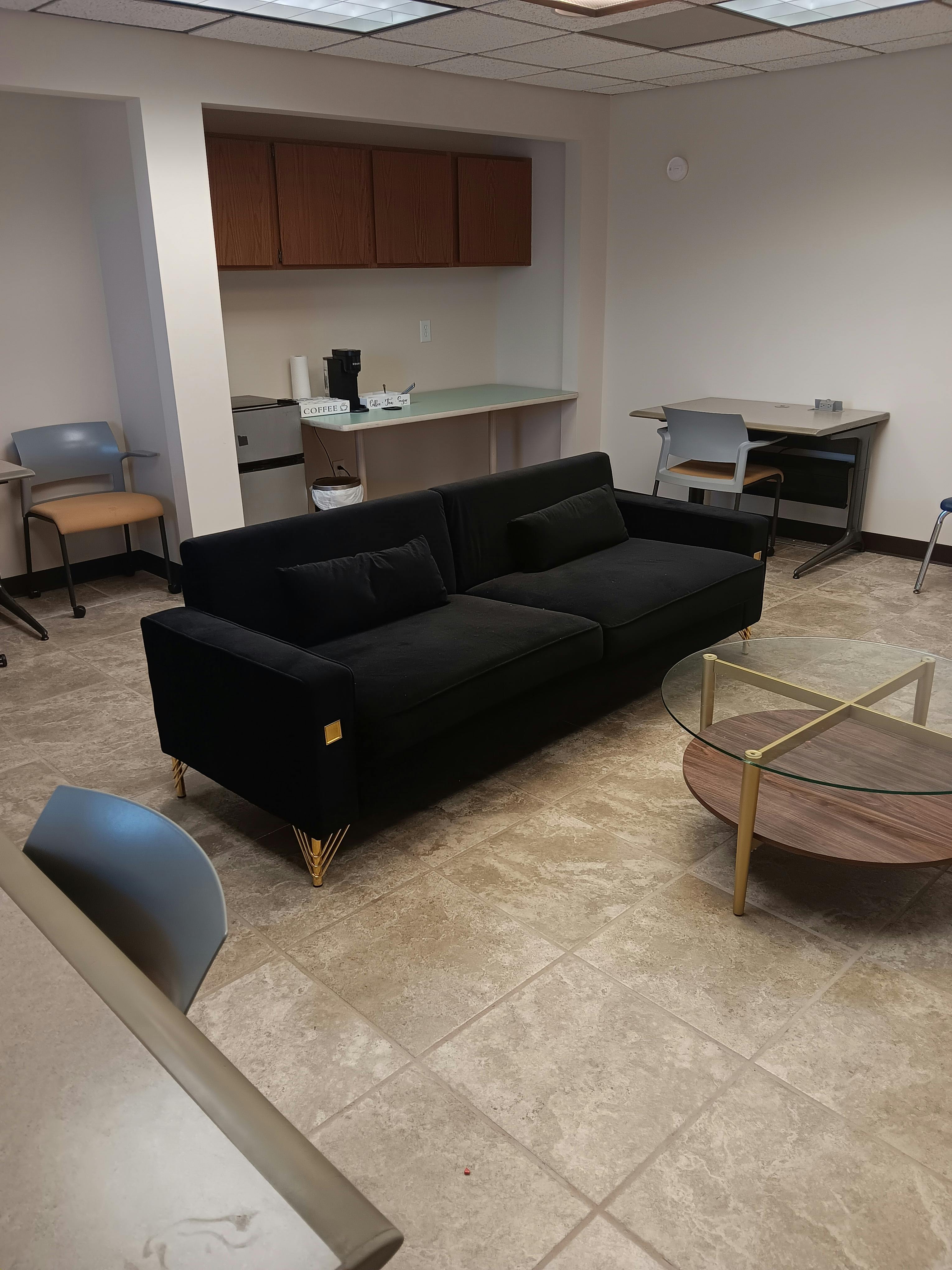 Black sofa and coffee table in a room with a counter and cabinets