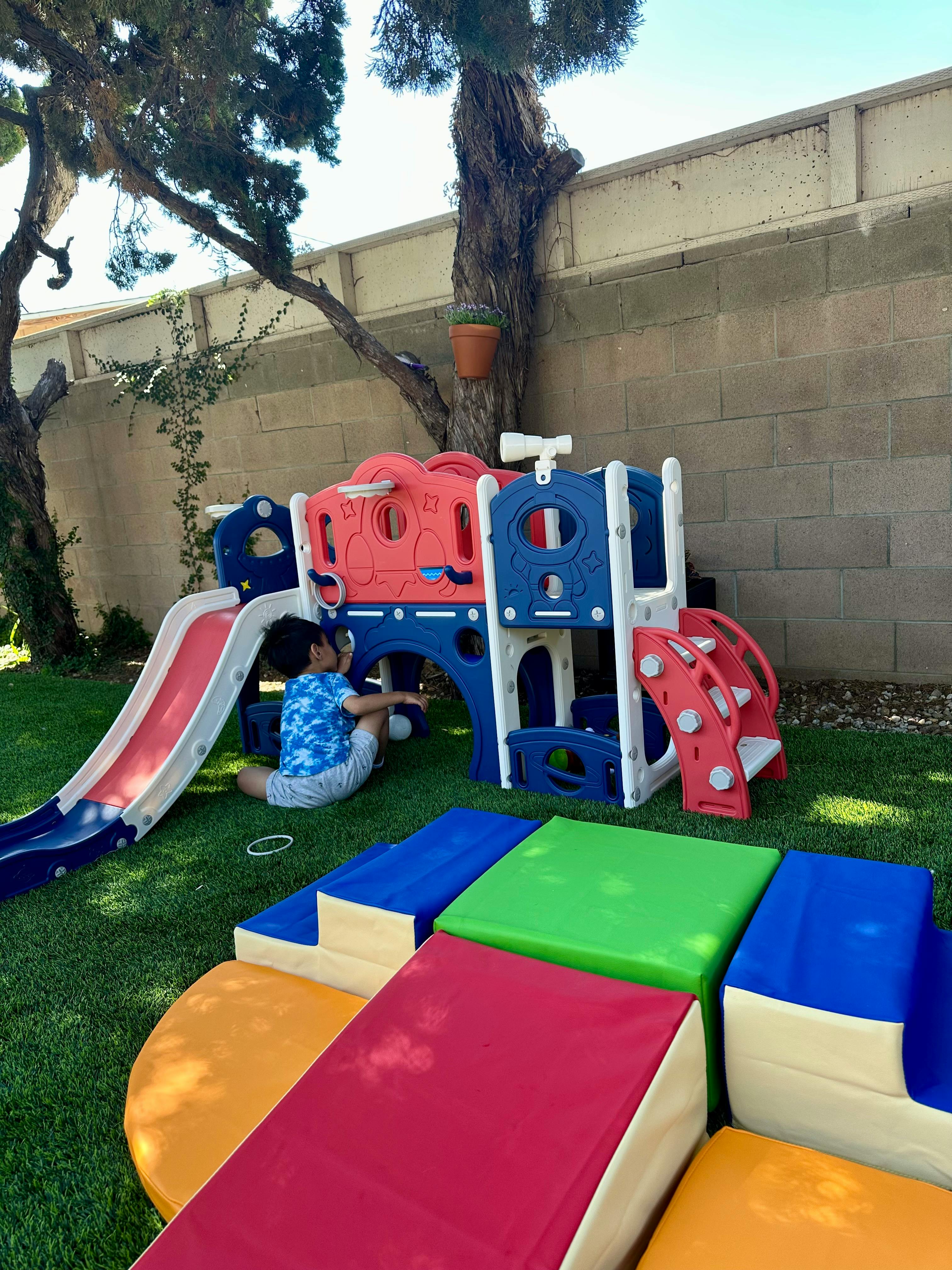 Child playing on a colorful outdoor playset with a slide